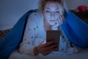 girl looking at phone in bed 