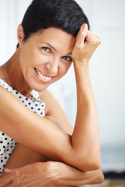 Woman With Hand on Head Smiling